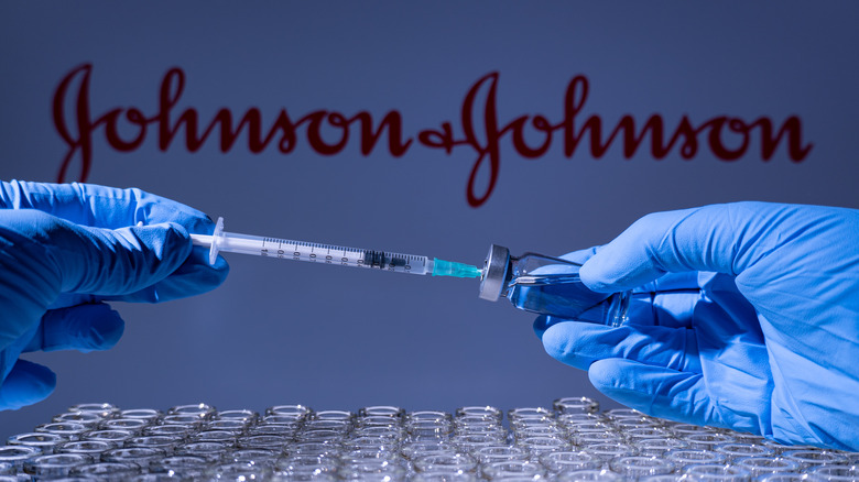 Gloved hands pulling syringe our of Johnson & Johnson vaccine vial