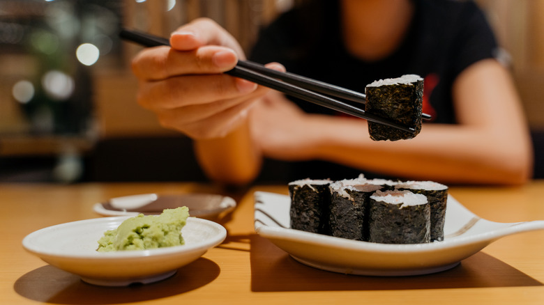 Woman eating wasabi with sushi