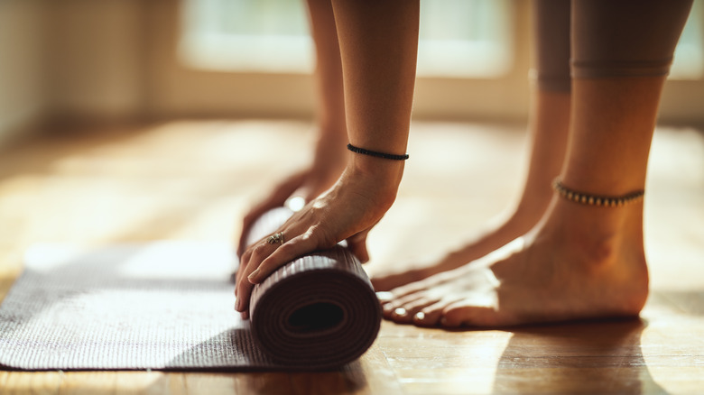 Close-up of a woman's hands rolling up exercise mat 