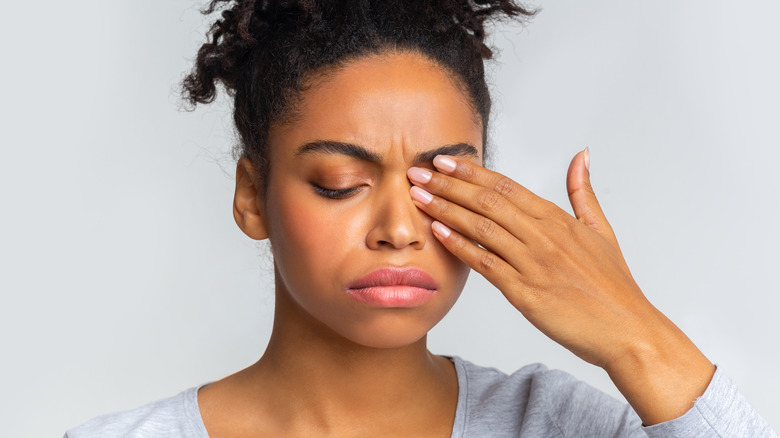 Woman rubbing her left eye