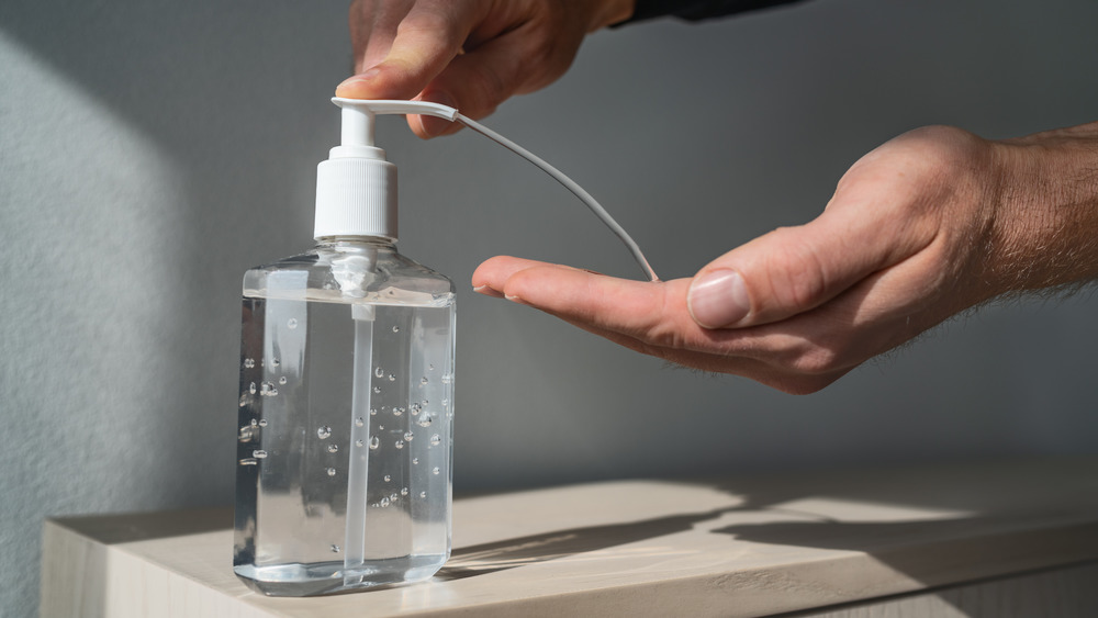 close up of hand sanitizer squirting out of bottle into man's hand