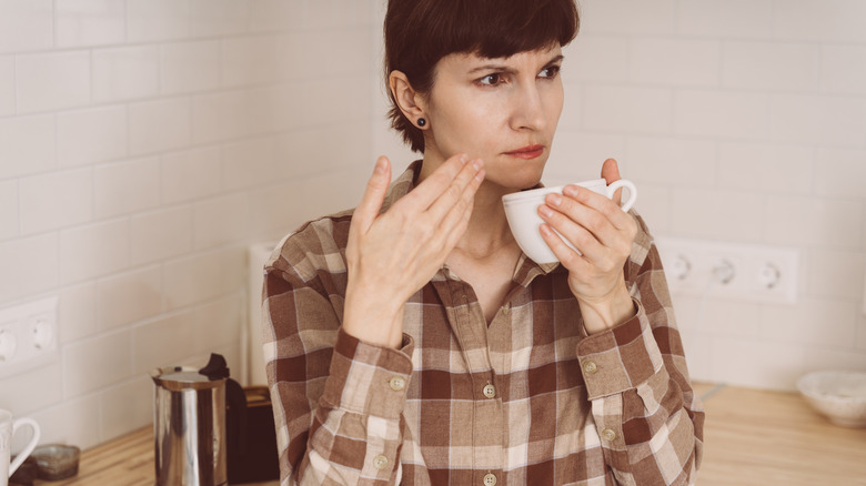 Woman struggling to smell coffee cup