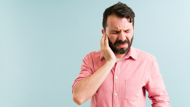 man holding ear in pain