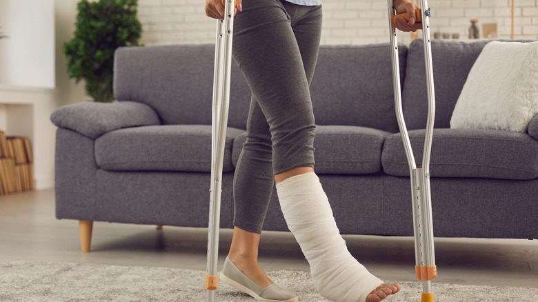 Woman walking with leg cast and crutches