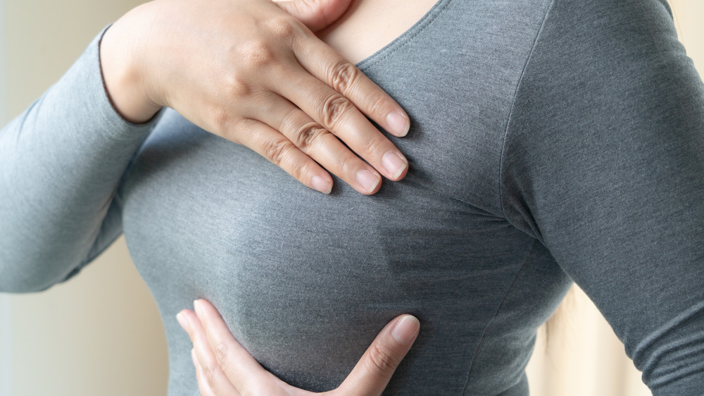 Woman's hands checking breast for lumps