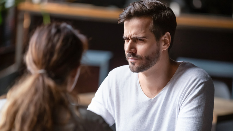 man in a white shirt looking skeptical at a woman 