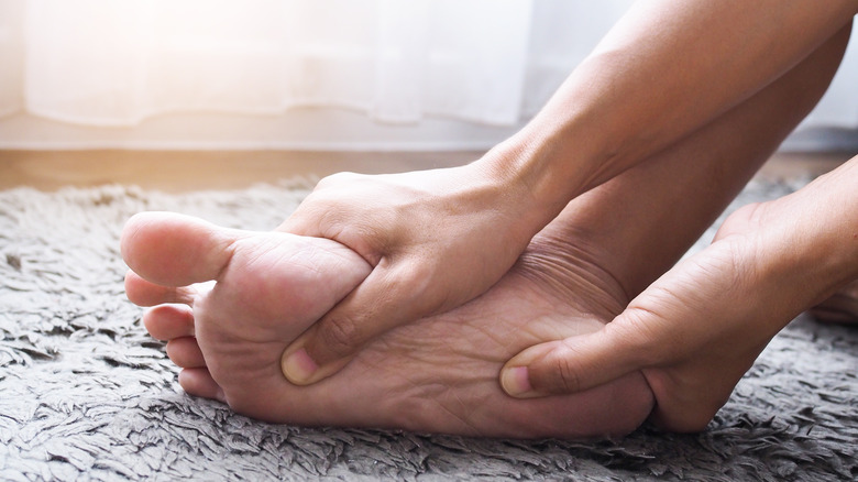 Pair of hands rubbing their foot on a gray rug