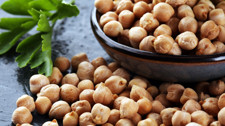 Chickpeas spilling over a bowl with green leaf