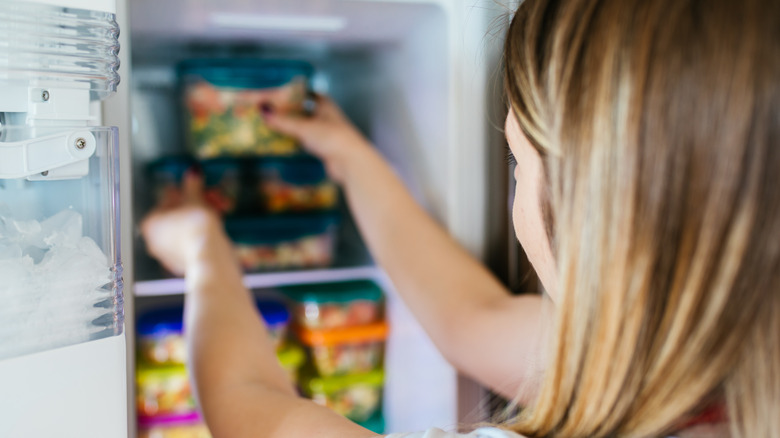 woman putting a container in the freezer