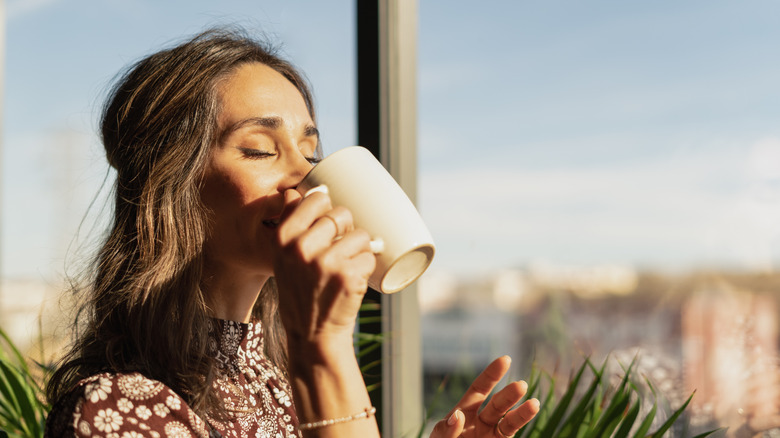 A woman enjoying a drink from a mug
