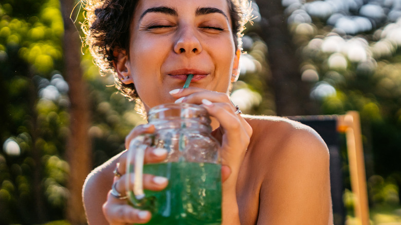 Woman drinking green drink outdoors