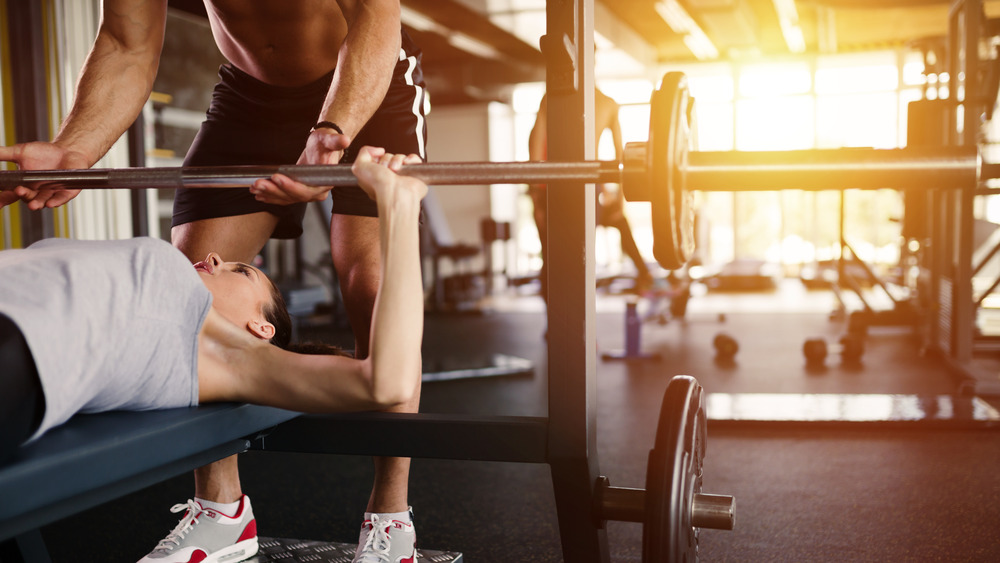 A trainer helping their client with a bench press set
