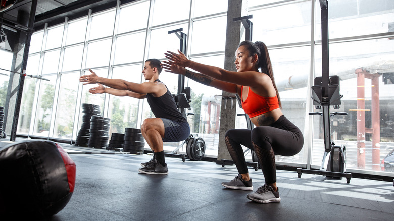 Two people doing squats in a gym