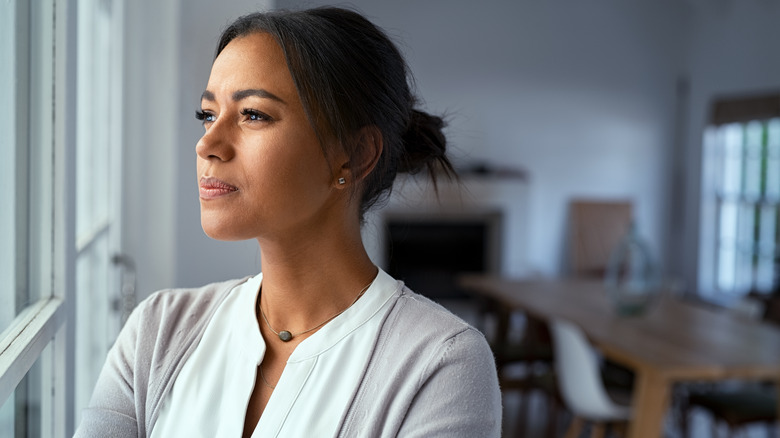 worried African American woman looking through window