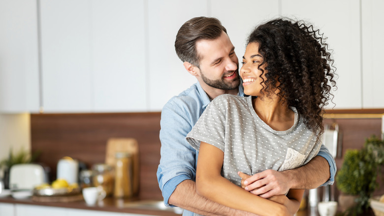 a man hugs his lady lovingly in the kitchen