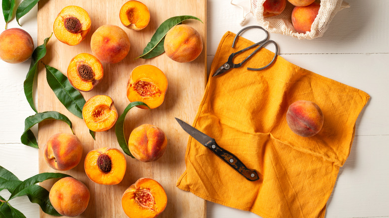 peaches on a cutting board with a knife