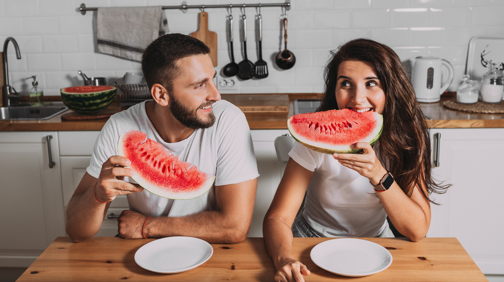 A couple eats watermelon at the table