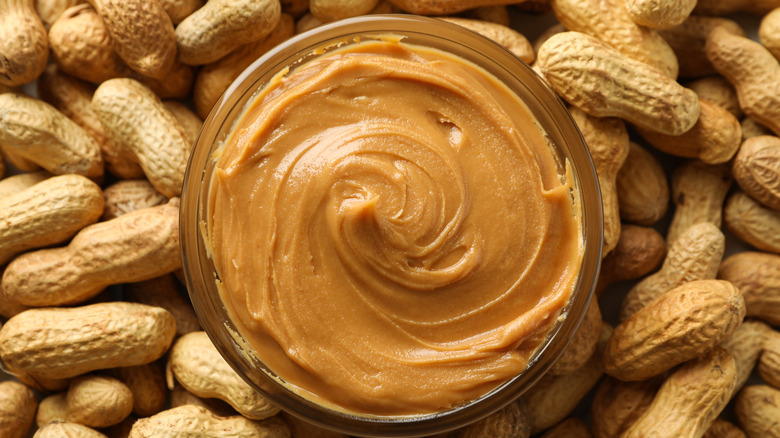 jar of peanut butter surrounded by peanuts