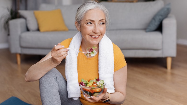 older, fit woman eating a salad