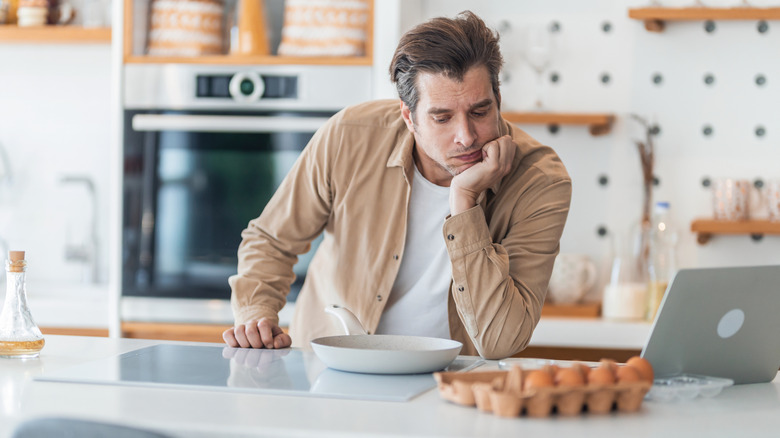 man considering how to make eggs in kitchen