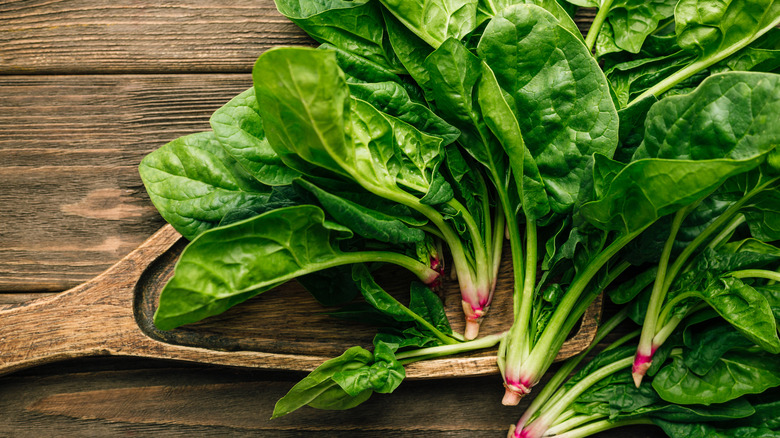 Fresh spinach sitting on wooden cutting board