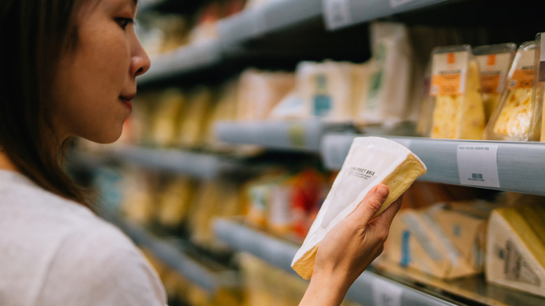 A woman shopping for cheese at a supermarket