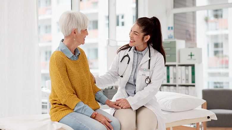 smiling doctor sitting on exam table beside patient