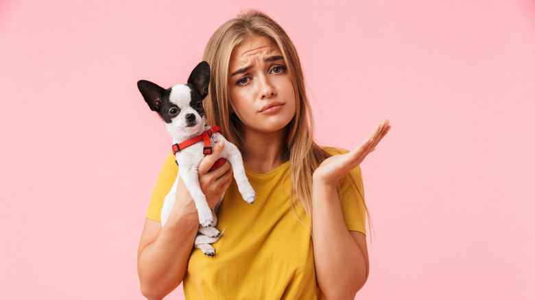 confused woman holds dog