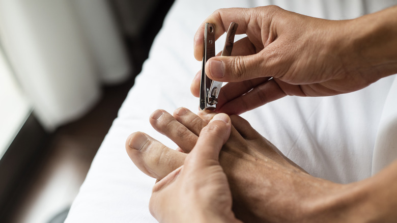 A close-up of a man clipping his toenails