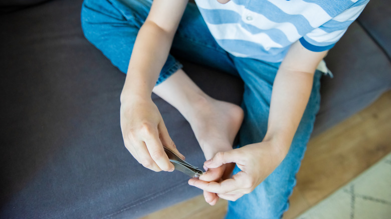 A young boy clipping his toenails