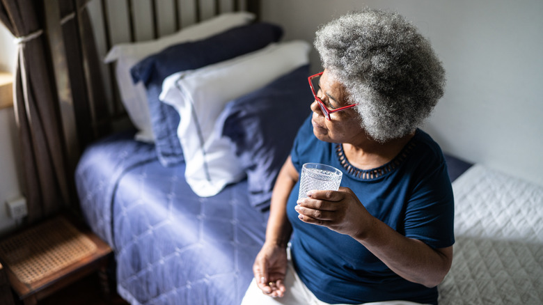 Woman seated on bed taking medication