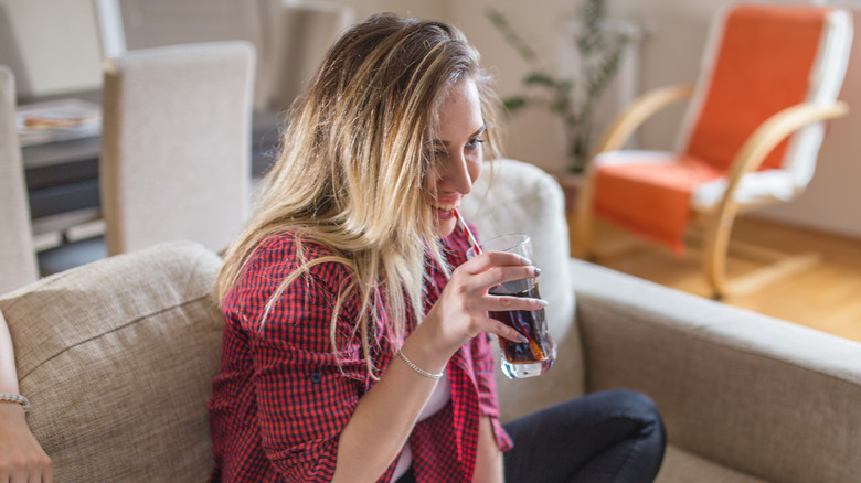 Smiling woman drinking soda on couch