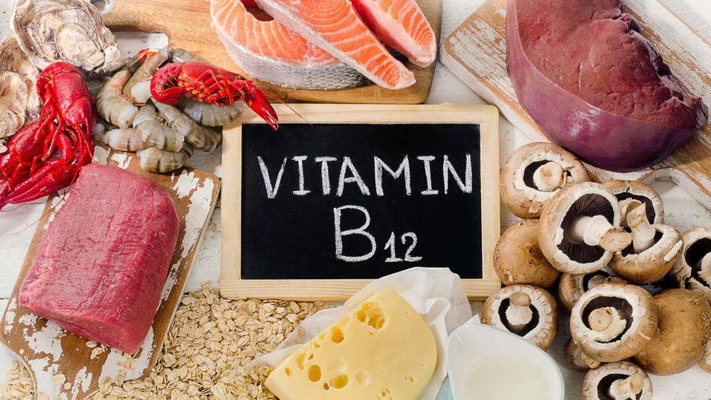 Seafood, meat, cheese, mushrooms surrounding a chalkboard with 'Vitamin B12' written on it