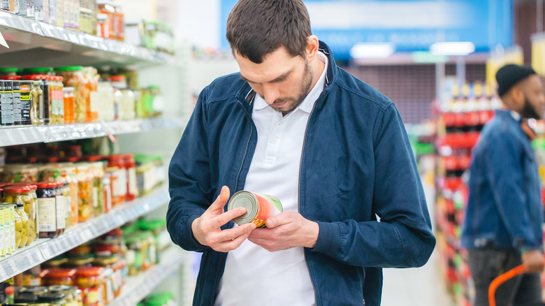 man looking at can label 