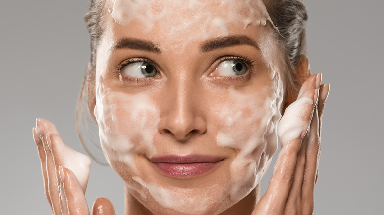 close up of woman with foaming cleanser on face