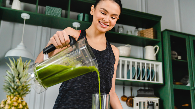 Woman pouring green smoothie into glass