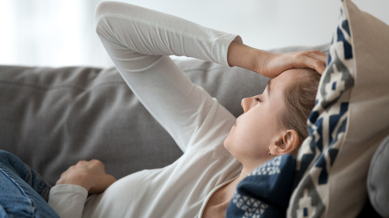 woman lying on couch with hand on head