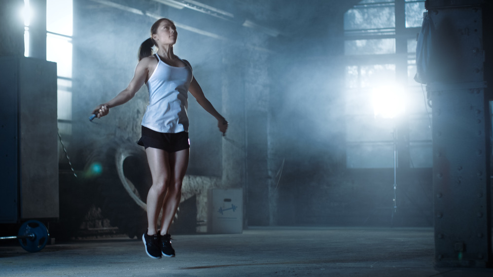 Woman jumps rope in what looks like a warehouse