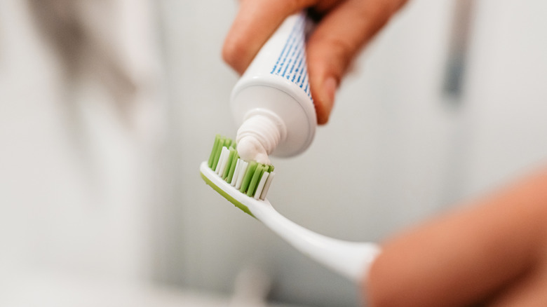 man putting toothpaste on toothbrush