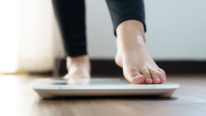 woman stepping on scale to look at weight at home
