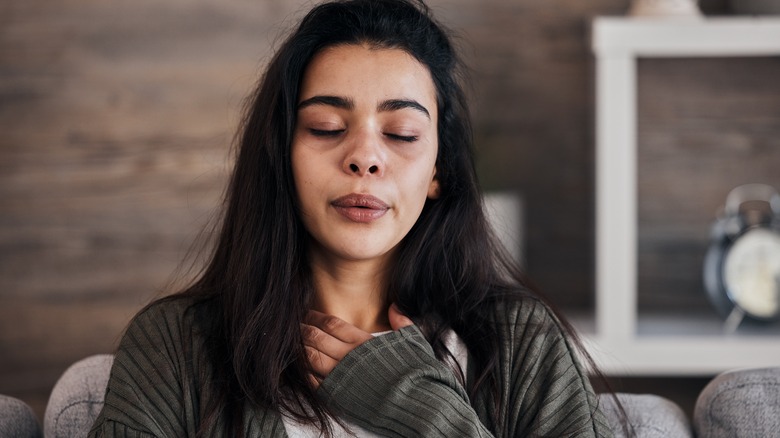 woman holding her chest to calm herself