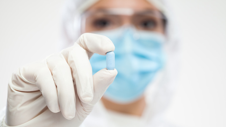 healthcare worker holding up pill