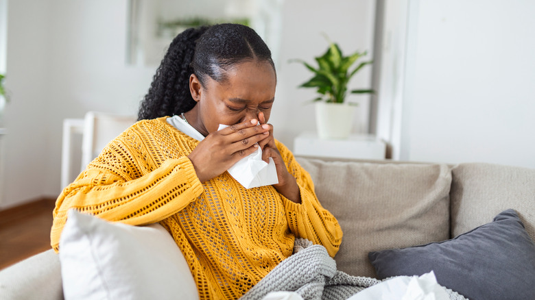 woman on couch blowing her nose