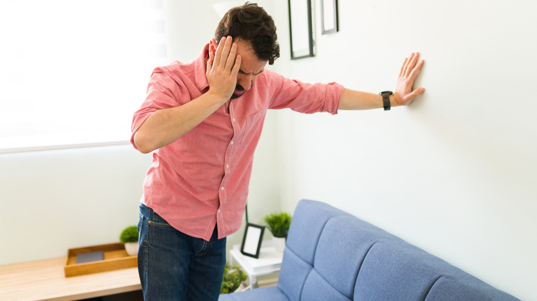 Man feeling dizzy against wall