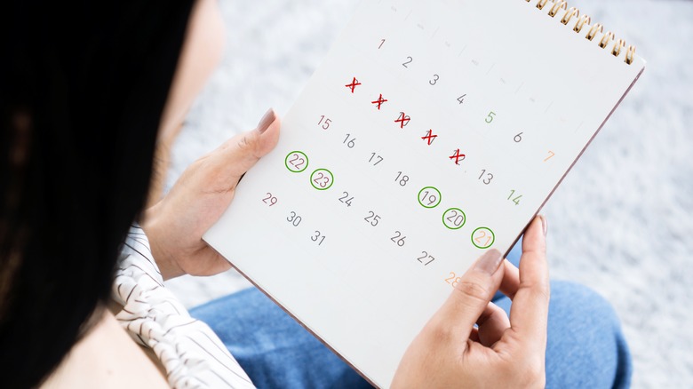 a woman holds a period tracking calander 