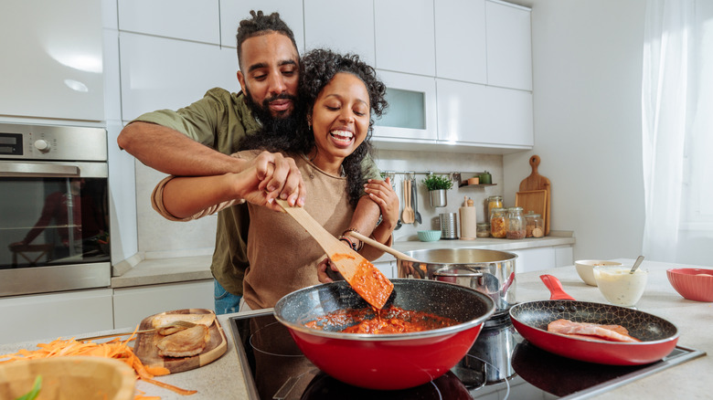 Smiling couple cooking in kitchen