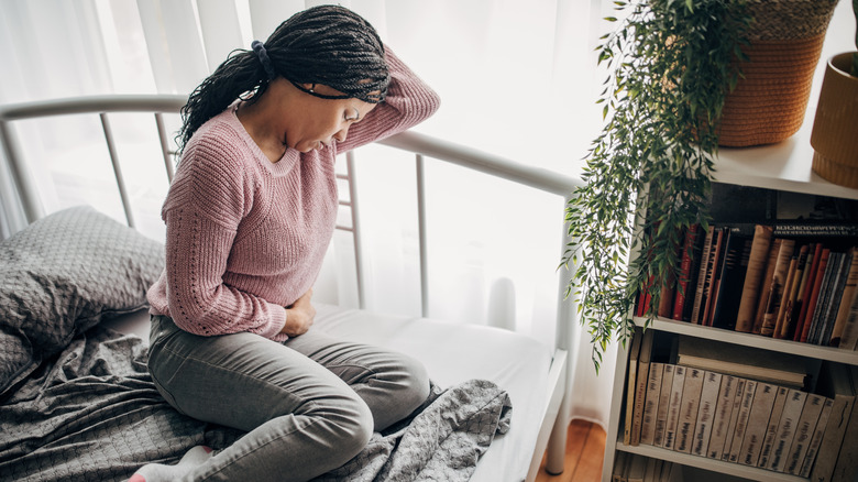 Woman sitting in bed with stomach ache