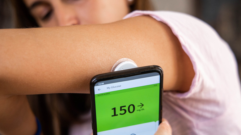 woman measuring blood sugar using device on arm