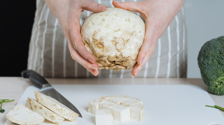 woman holding peeled celeriac above cutting board