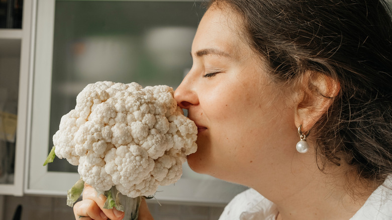 smiling woman sniffing cauliflower
